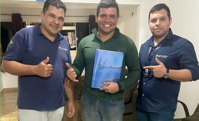 Robson do Nascimento com a pasta do projeto entre dois integrantes da equipe DP2, fazendo sinal de positivo