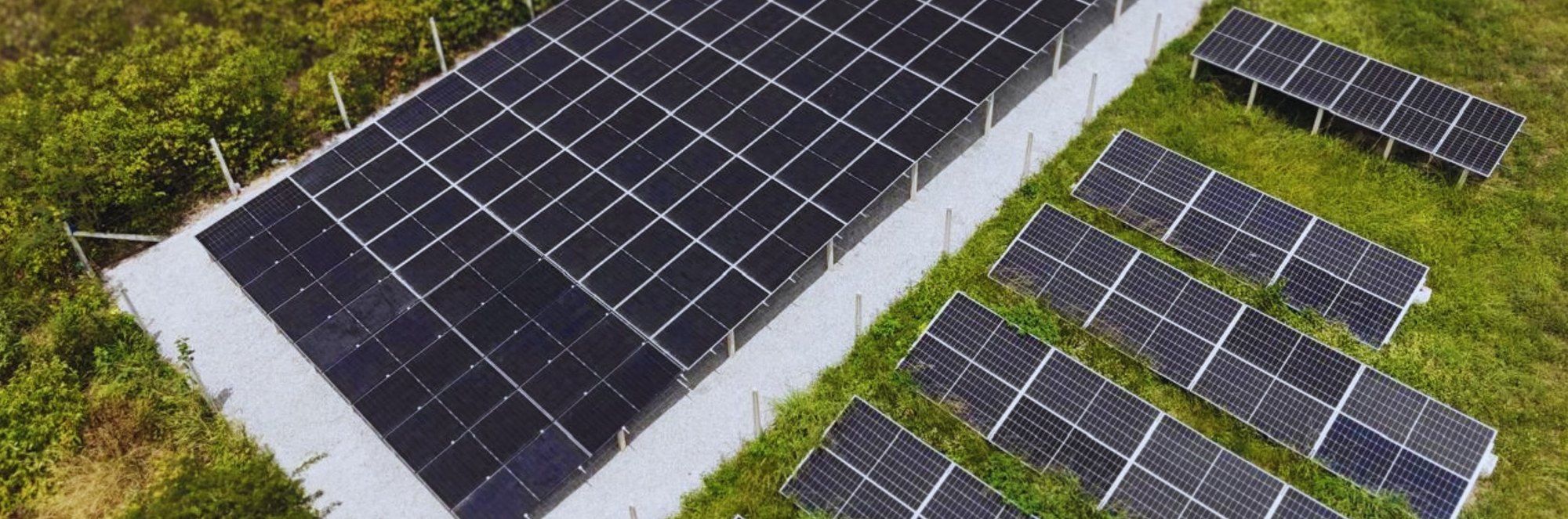 Usina solar de solo em Recife com fileiras de módulos sobre brita, cercada por vegetação