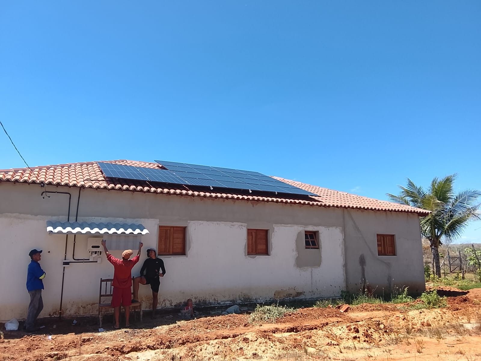 Cliente e equipe da DP2 comemorando em frente à casa do sítio com a usina solar recém-instalada no telhado